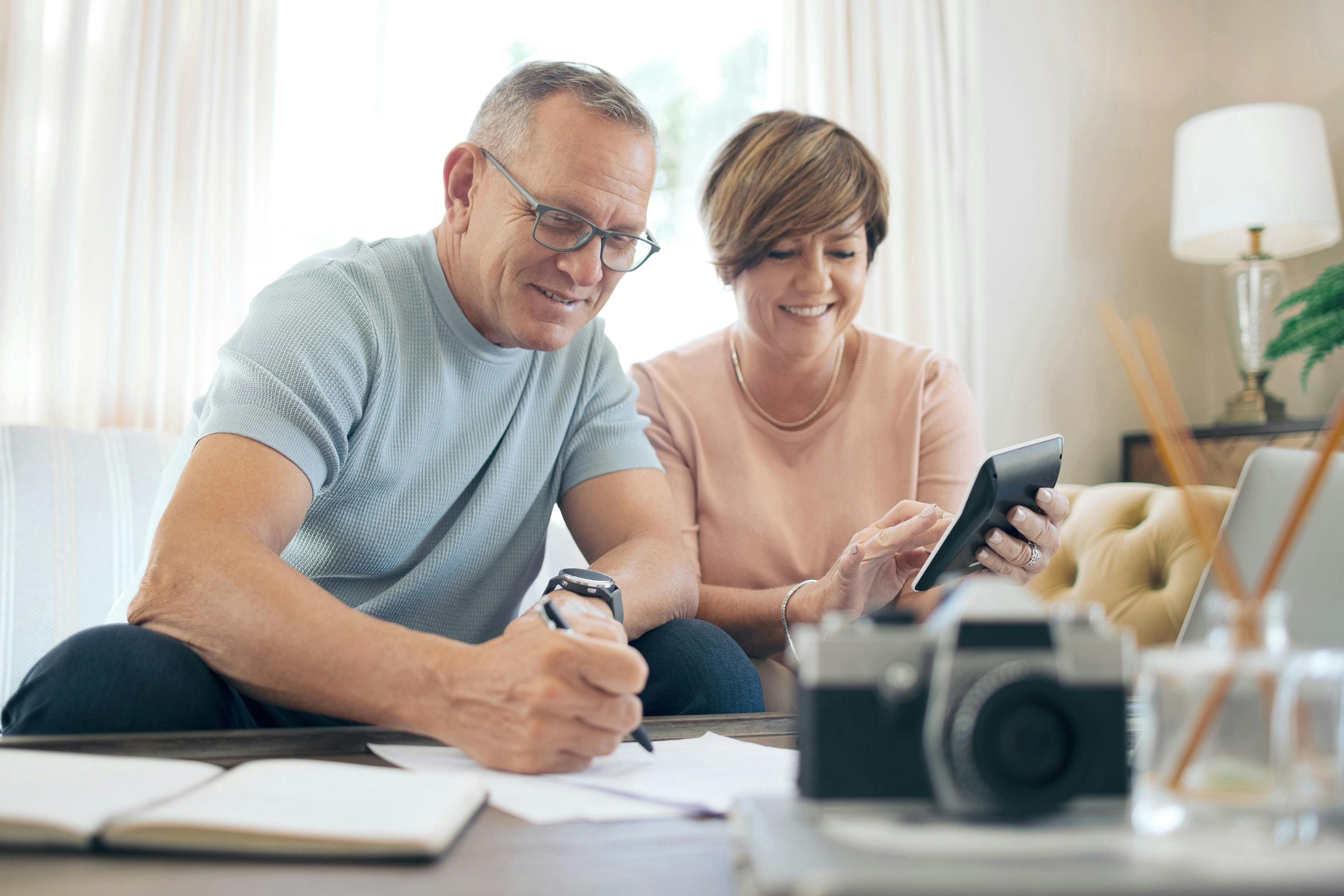 Et eldre par som sitter i stua og bruker kalkulator for å ta beste avgjørelse når de skal samle lån.