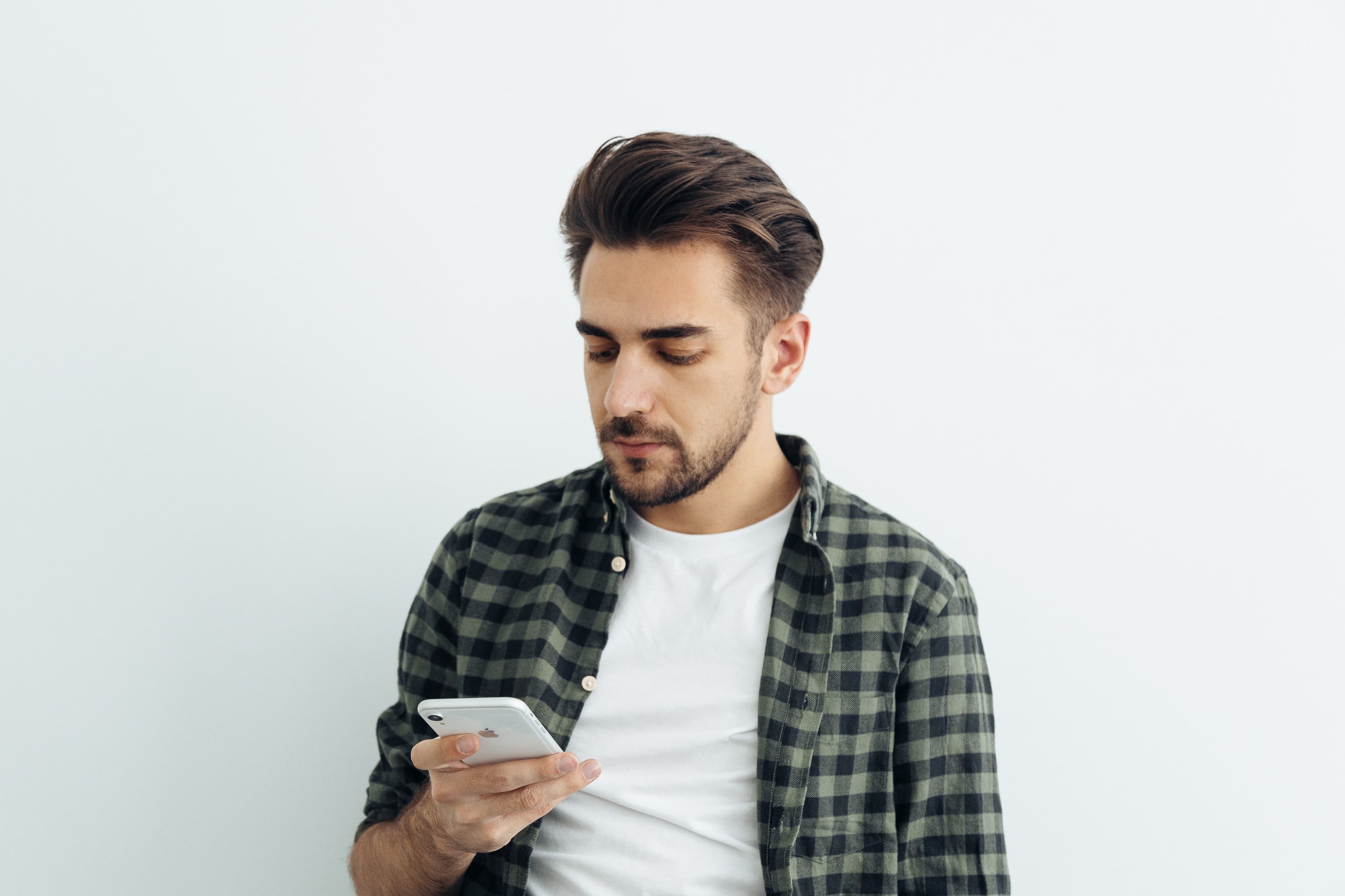 En mann som bruker sin iphone til å øve på teoritentamen fra Testen.no slik at han kan bestå teoriprøven.
