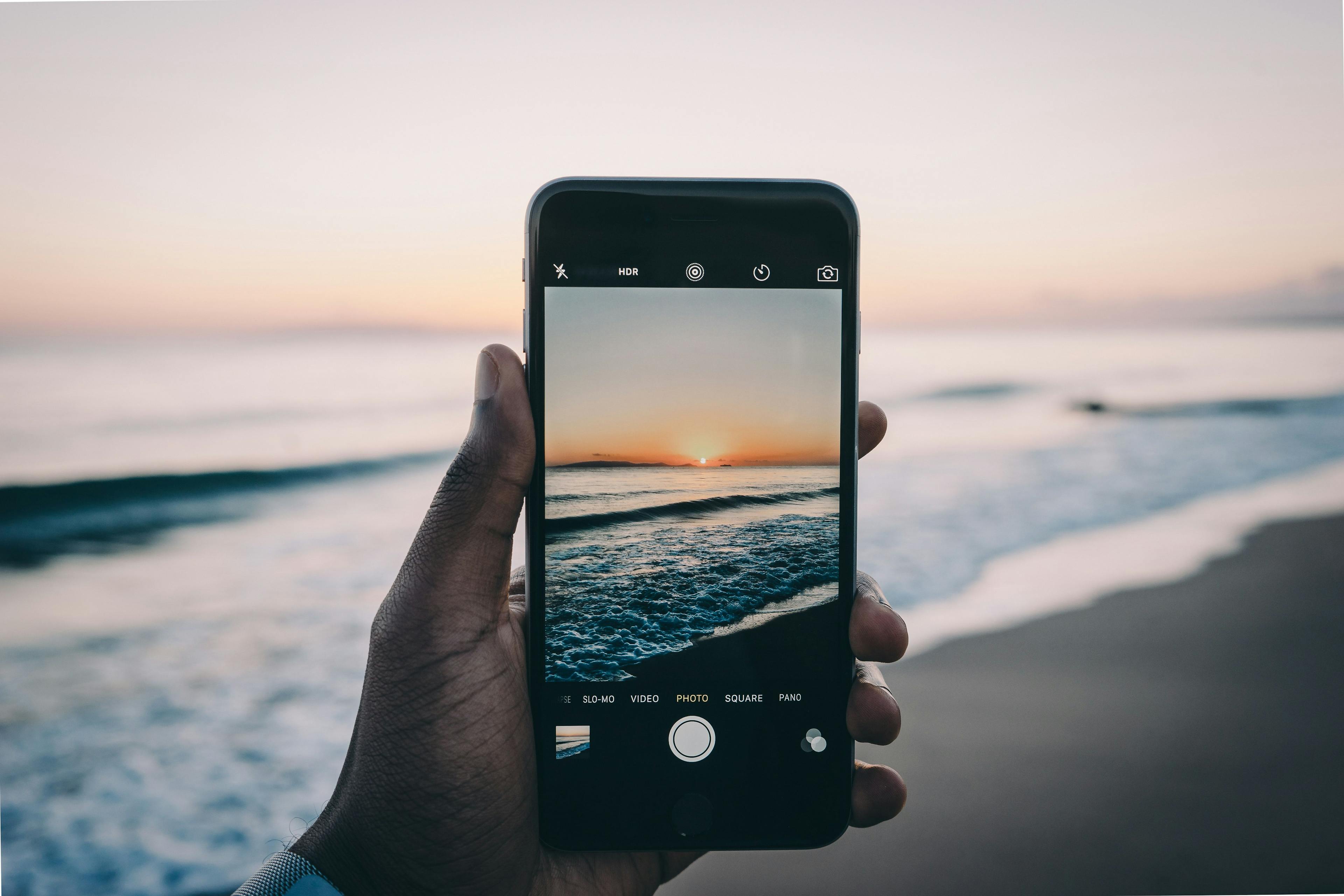 Mobiltelefon som tar bildet av en strand etter bytte av mobilabonnement.