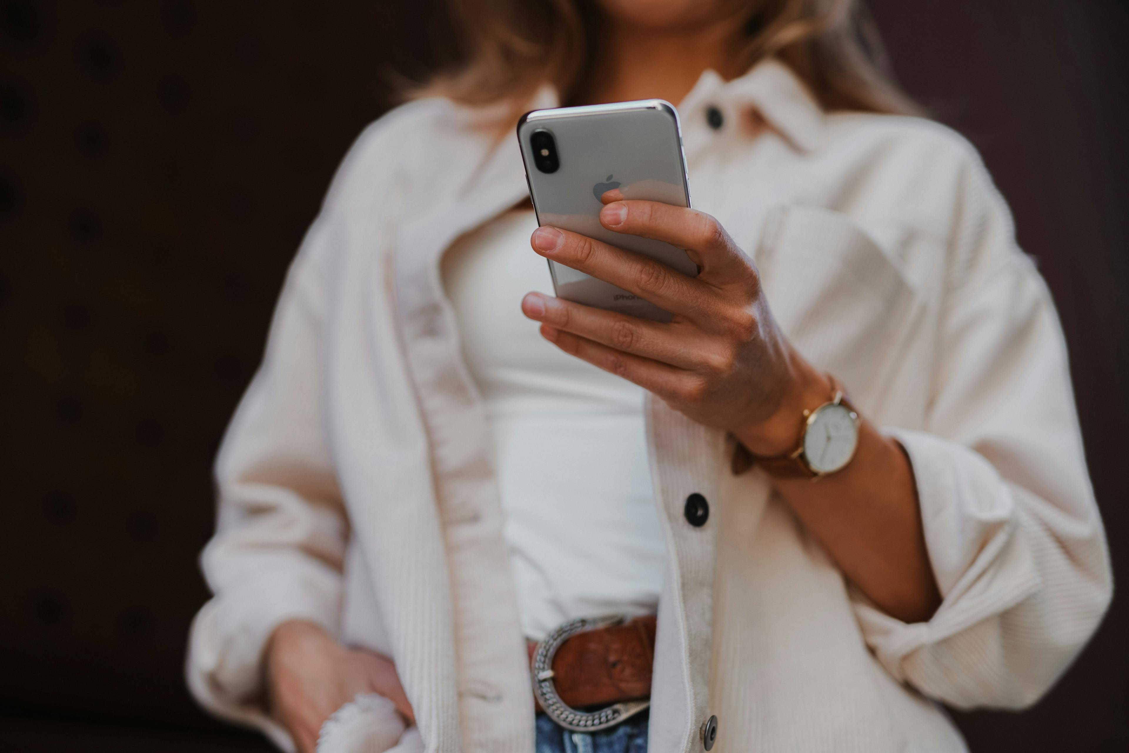 Ei dame kledd i hvitt som bruker mobilen sin som hun har mobilabonnement med fri data på.