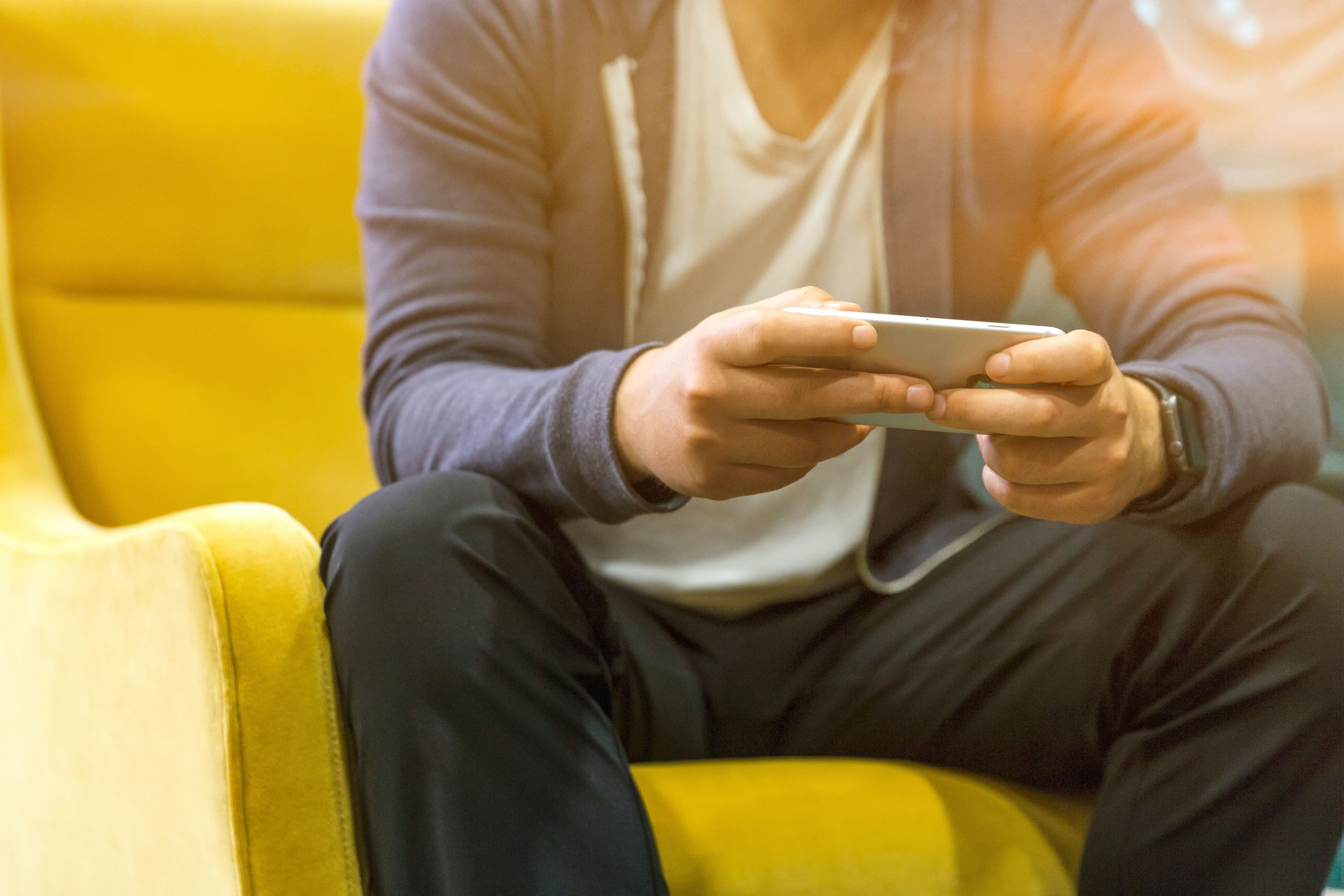 En mann som sitter hjemme med sin telefon etter Ă„ ha lest hvordan velge riktig mobilabonnement.
