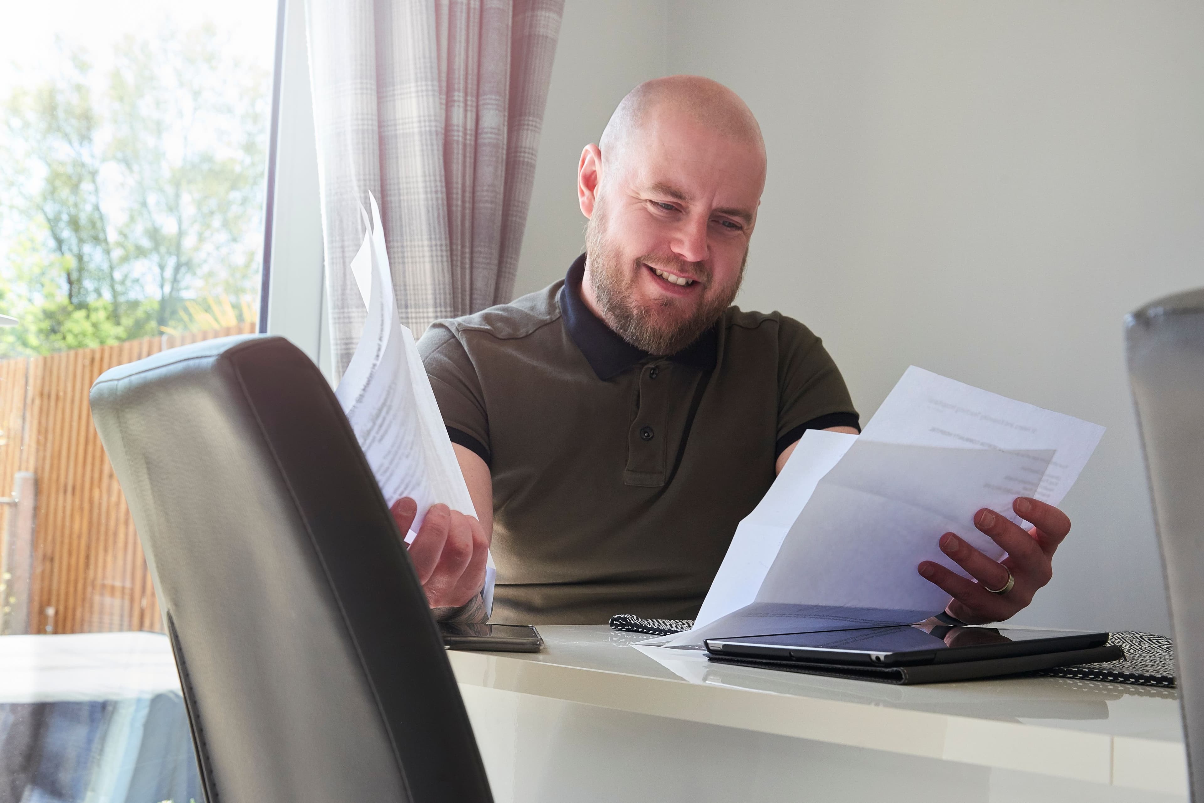 En mann som sitter på kjøkkenet sitt og har fått svar etter søk om raske smålån.